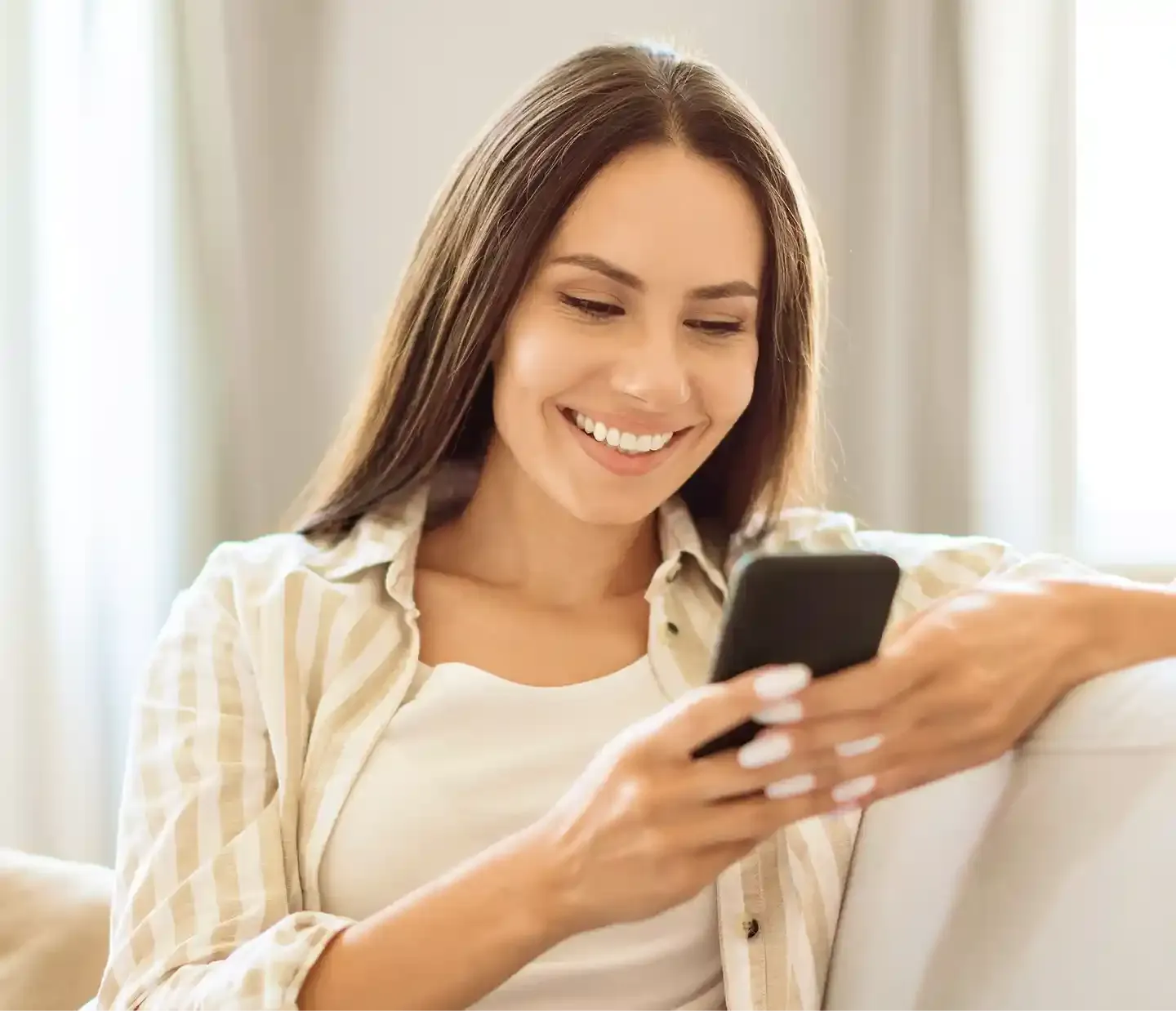 A person relaxing at home, smiling while using Yuna on their phone.